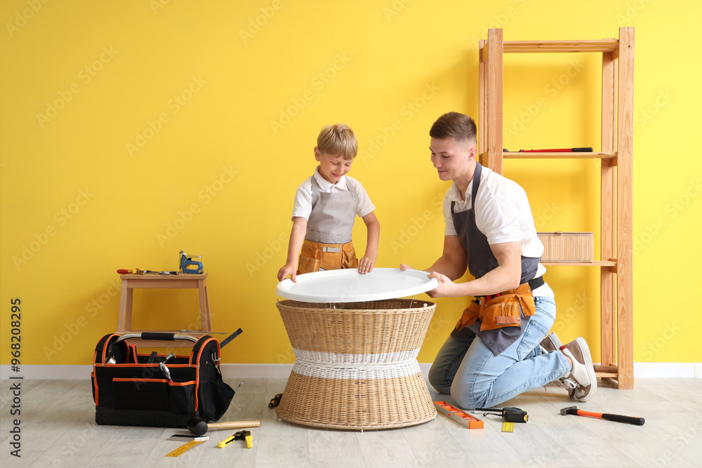 Male worker with his little son assembling table in room