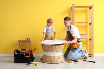 Wall Mural - Male worker with his little son assembling table in room