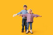 © Pixel-Shot - Happy brother and sister in winter clothes on yellow background