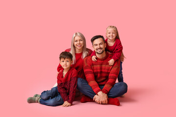 Poster - Happy family with children in winter clothes sitting on pink background