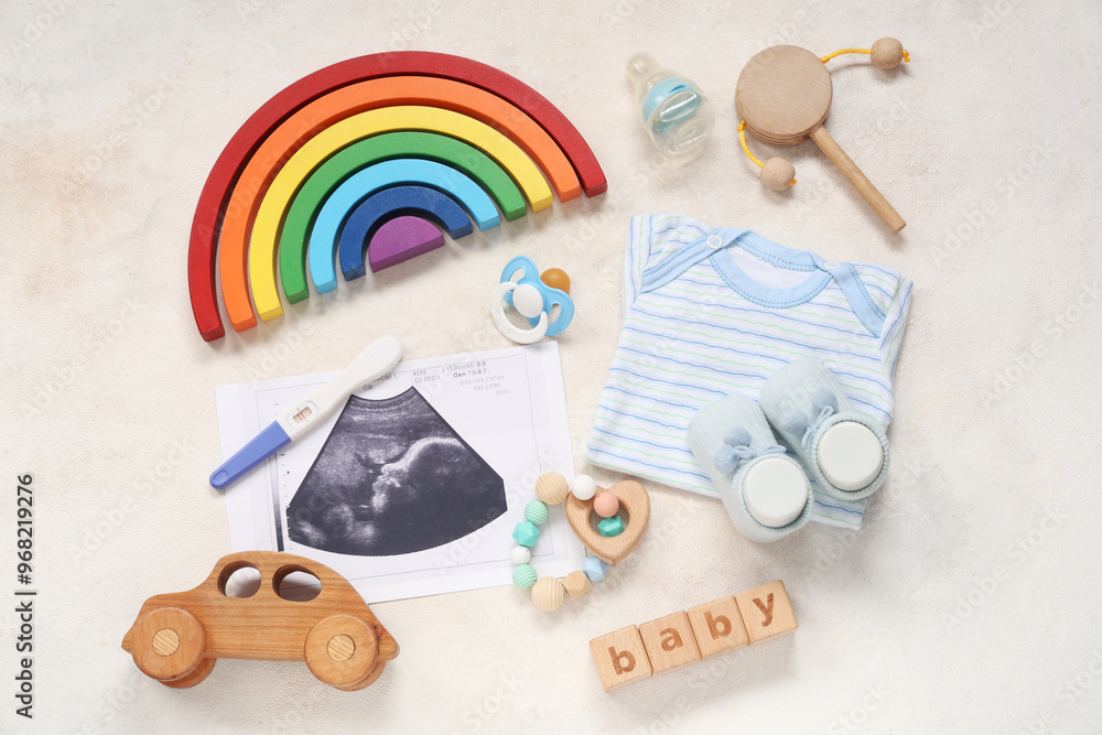 Composition with clothes, sonogram image, pregnancy test and word BABY on grunge white background