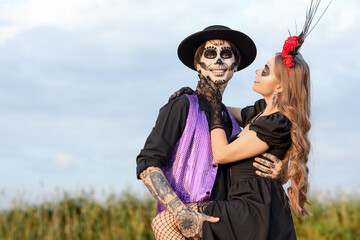 Young happy couple dressed for Mexico's Day of the Dead (El Dia de Muertos) in park outdoors