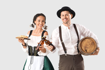 Wall Mural - Happy mature waiters in traditional German clothes with bottles of beer and pretzels on grey background