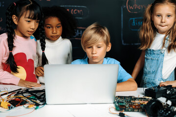 Wall Mural - In classroom student in STEM class learning about coding robotics car. Smart children watching at laptop and thinking seriously but a child in bib play with a remote car and look at camera. Erudition.