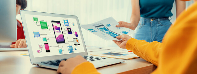 Panorama banner of startup UX developer or company employee design user interface or UI prototype for mobile application or website software with software display on laptop monitor in office. Synergic