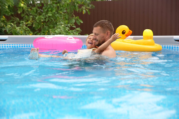 Wall Mural - Happy daughter and her father having fun in swimming pool