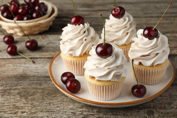 Wall Mural - Delicious cupcakes with cream and cherries on wooden table, closeup