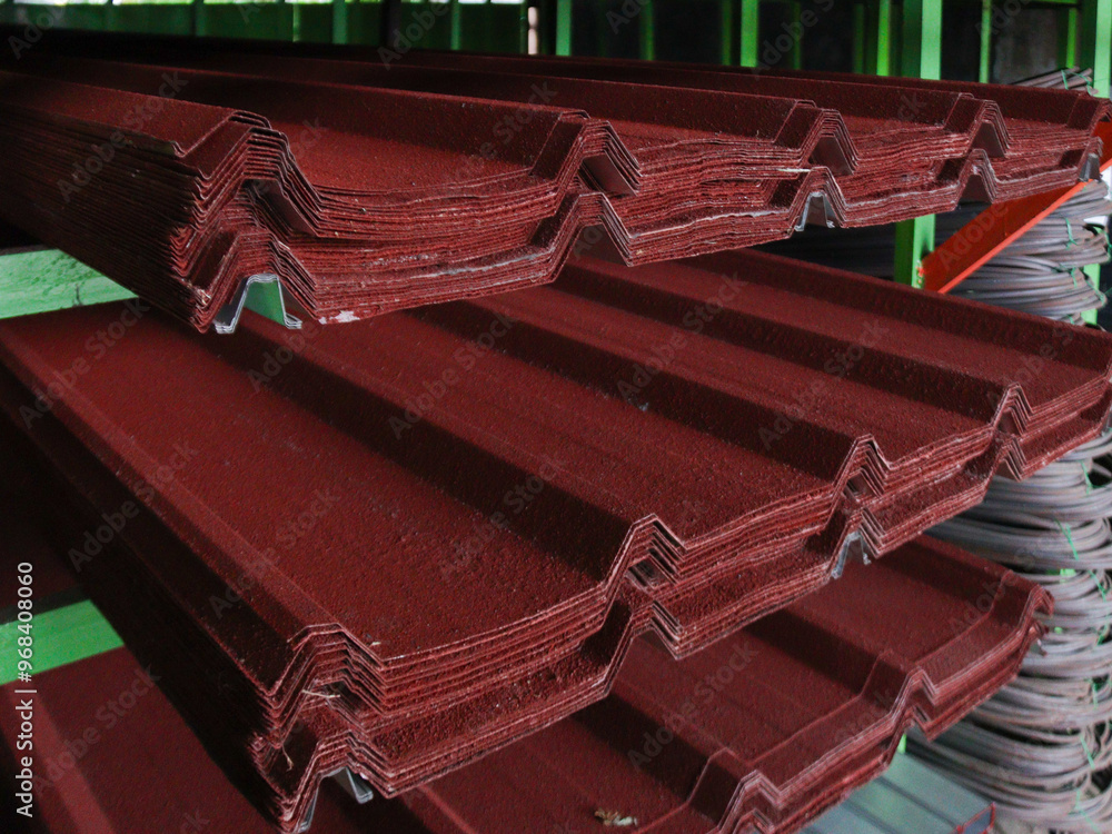 Close-up of red corrugated metal roofing sheets stacked in a warehouse ...