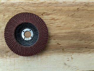 Flap disc. Sandpaper grinding blade on wooden board. Round sandpaper for smoothing wood. Carpenter's tool kit.