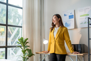 Wall Mural - young asian businesswoman leaning on desk and looking out window