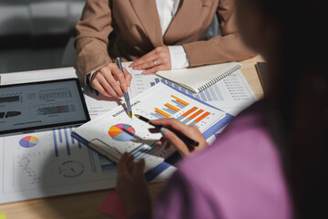 Two businesswomen are sitting at a table in a conference room, talking, discussing, meeting, financial business information. Online marketing, information, documents, laptop in modern office.