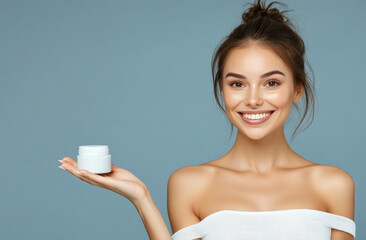 Poster - A beautiful woman with brown hair in an elegant bun, smiling and looking at the camera while holding out her hand to appear cream or serum on it.