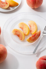 Wall Mural - Cut peaches on a plate on white background.