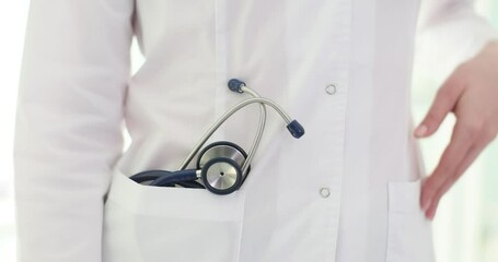 Sticker - Health care worker adjusts his white coat, showing stethoscope hidden in pocket, standing in medical clinic