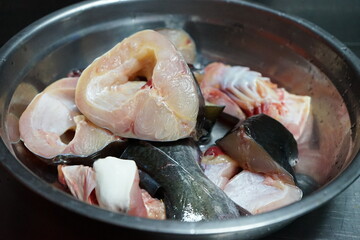 Closeup pieces of raw fish in the stainless bowl during the preparation for cooking