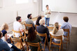 © Johnér - High angle view of smiling businesswoman giving presentation to coworkers against blank projection screen at office