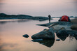 © Johnér - Army soldier looking through binoculars while standing at lakeshore during sunset
