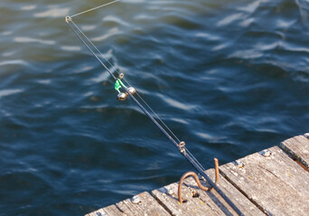 Sticker - A fisherman's fishing rod on a wooden bridge on a lake