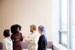 © Johnér - Businesswoman discussing with team mates while standing at office