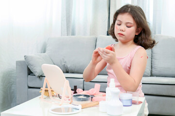 Little girl enjoys to play with makeup in the living room. Cute girl happy with various makeup tools.Happy holidays concept...