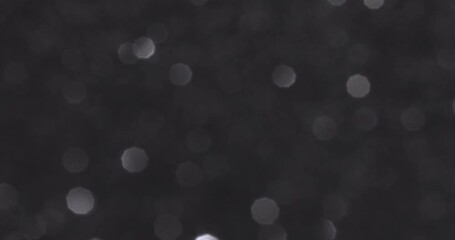 black bokeh background. shiny white sparkles on black background
