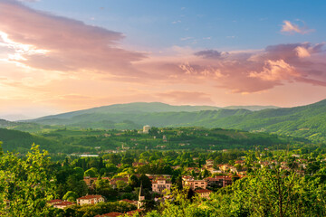 travel summer view from hill to a nice european town with amazing buildings, green hills and mountains with amazing cloudy evening sky on background