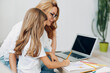 © SHOTPRIME STUDIO - Mother and daughter at a table with a laptop and pencils, engaging in creative activities together