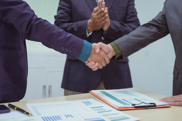 Wall Mural - Close-up of business people shaking hands during a meeting in the office, discussing and analyzing charts,financial data,planning digital marketing projects together with business experts investors