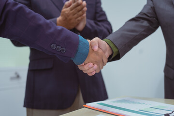 Wall Mural - Close-up of business people shaking hands during a meeting in the office, discussing and analyzing charts,financial data,planning digital marketing projects together with business experts investors