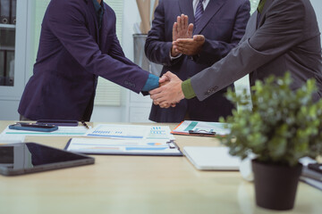 Wall Mural - Close-up of business people shaking hands during a meeting in the office, discussing and analyzing charts,financial data,planning digital marketing projects together with business experts investors