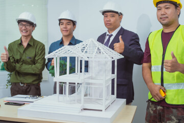 A male engineer and  contractor at a desk in an office discuss the structural design of a house,roof drafting, lot size and number of occupants for a dream home project,focusing on budget and style