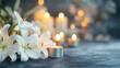 © thanakrit - White lily flowers with lit candles on grey background
