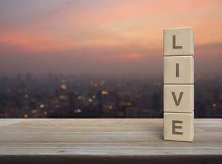 Wall Mural - Live letter on wood block cubes on wooden table over blur of cityscape on warm light sundown, Technology broadcasting communication concept