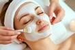 © antusher - Woman receiving facial mask in spa salon, close-up of hands applying white cream