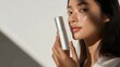© Heng Heng - AI Stock - Portrait of a thoughtful Asian female model holding a skincare product,with a serene and peaceful expression. The image showcases the importance of a natural.