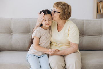 Cheerful cute granddaughter kid and happy grandma hugging with love, tenderness, affection, Grandmother embracing grandchild, enjoying family relationship.