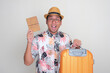 © KrishnaTedjo - A man showing amazed expression while holding travel document and carrying luggage