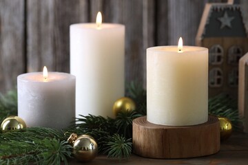 Wall Mural - Burning candles, baubles and fir branches on wooden table, closeup. Christmas atmosphere