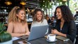 © Pinklife - Three friends seated in a cafe, engaged in a joyful conversation, with a laptop and coffee, displaying a moment of connection, warmth, and togetherness in a modern setting.