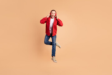 Canvas Print - Full length portrait of nice young man touch headphones jump wear red shirt isolated on beige color background