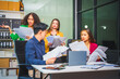 © Phushutter - Asian colleagues, middle-aged man and young woman, happily collaborate in office workplace. They gather around laptop, discussing project management, startup plans, teamwork paper stacks on desk.
