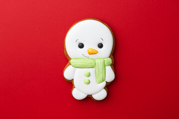 Wall Mural - Tasty Christmas cookie in shape of snowman on red background, top view