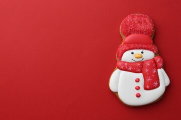 Poster - Tasty Christmas cookie in shape of snowman on red background, top view. Space for text