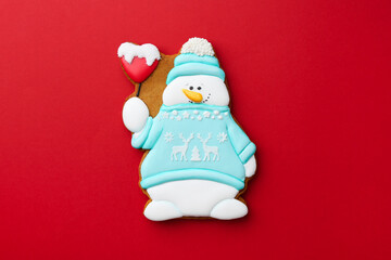 Wall Mural - Tasty Christmas cookie in shape of snowman on red background, top view