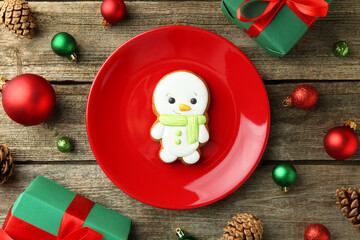 Wall Mural - Delicious cookie in shape of snowman and Christmas decor on wooden table, flat lay