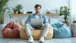 © CreativeArt - Young man working on his laptop while sitting in comfortable bag chairs amidst a bright and airy room filled with plants and natural light in the morning