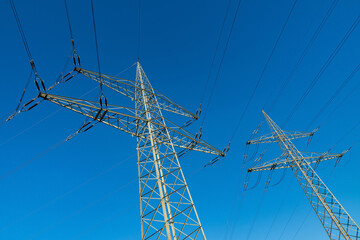 Tall electricity transmission towers against a clear blue sky