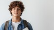 © mashimara - Confident teenage boy with curly hair holding notebooks, standing against a light gray background, ready for school. Education, youth, focus.