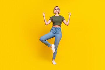 Poster - Full size photo of calm girl dressed khaki crop top hold balance on one leg in meditation pose isolated on yellow color background