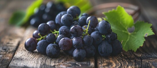 Wall Mural - A cluster of fresh black grapes on a wooden table is in selective focus. with copy space image. Place for adding text or design